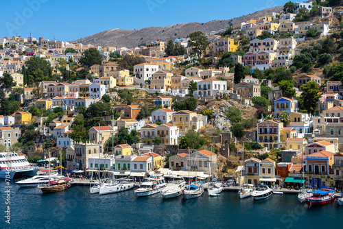 Yachts at pier of Symi island. Greek mountainous island and municipality, part of Dodecanese island chain. Harbor town of Symi and adjacent upper town Ano Symi