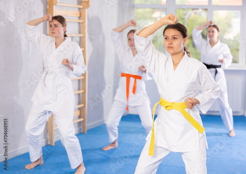 Kata karate woman teacher conducts female classes and performs movements and fighting techniques together with young girls students to prepare them for competitions.