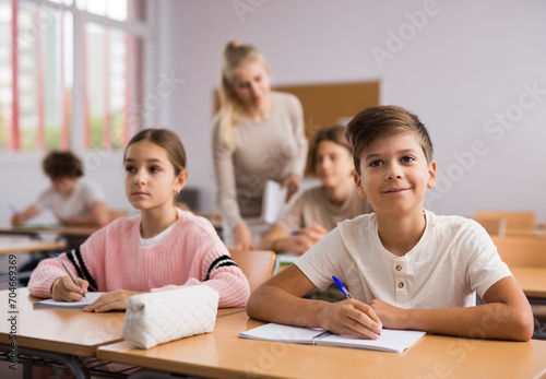 Portrait of teenage school girl and boy sitting together in classroom during lesson in secondary school