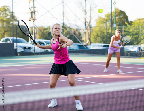 Sportive woman dressed in t-shirt and skirt playing tennis together with partner © JackF