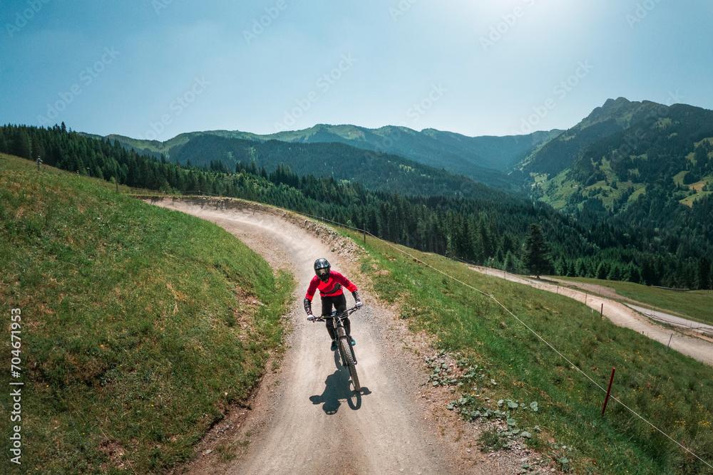 Downhill mountain biking in front of mountain scenery of Wilder Kaiser in the mountains of Austria, sunny blue sky day. Downhill mountain biking in front of mountain scenery of Wilder Kaiser in the mountains of Austria, sunny blue sky day.
