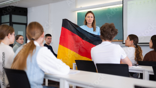 Confident young female professor shows students flag of Germany photo