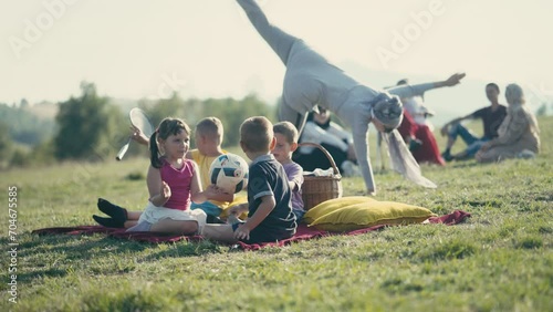 Muslim Woman Doing a Cartwheel Outdoors as Children Play and Adults Look at Her photo