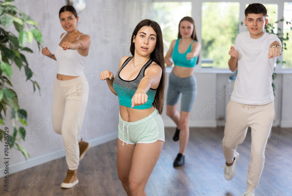 Portrait of determined hispanic teenage girl practicing basic punches during group self defense course