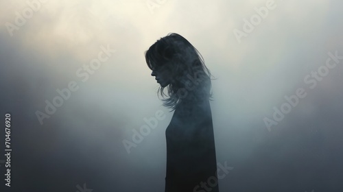  a woman standing in a foggy area with her head turned to the side and her hair blowing in the wind. photo