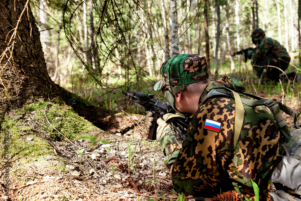 Russian soldiers man dressed military camouflage uniform with weapon in woodland at nature background, rear view. Male border guard in country border with autogun on war. Copy text space