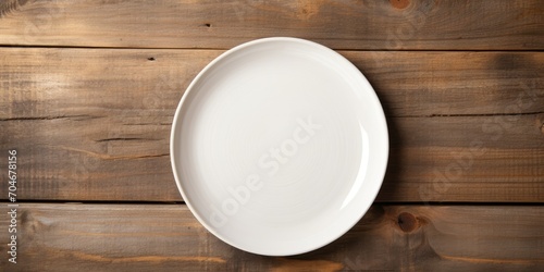 White wooden table top with copy space featuring an empty plate. Rustic kitchen mock up with craft paper.