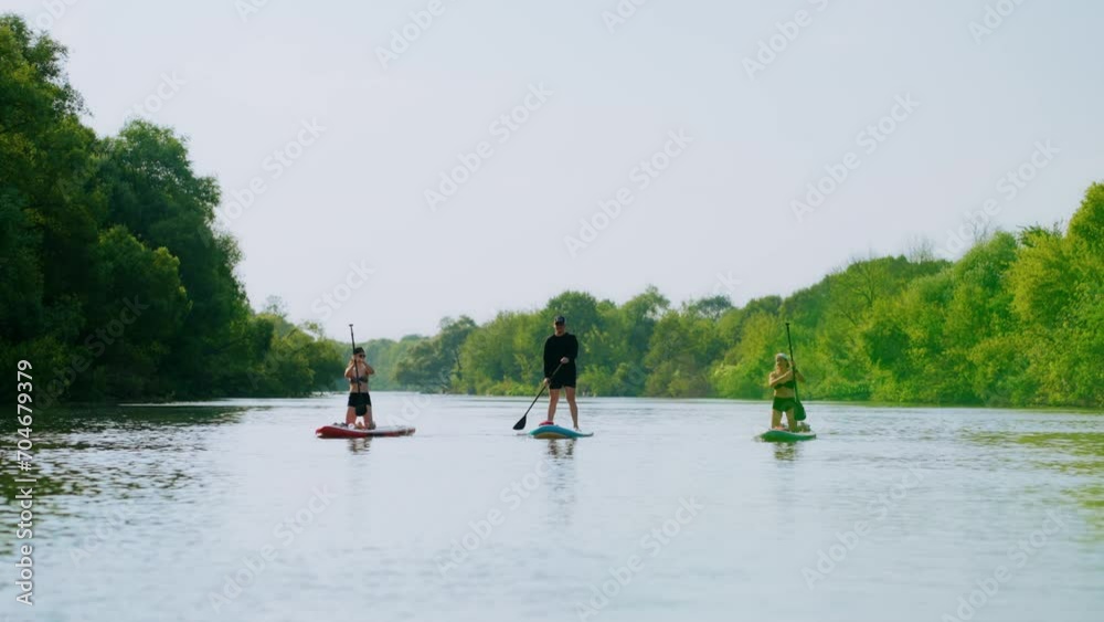 Group Rafting On SUP Boards In River In Summertime, Three People Floating On Inflatable Boards Group Rafting On SUP Boards In River In Summertime, Three People Floating On Inflatable Boards