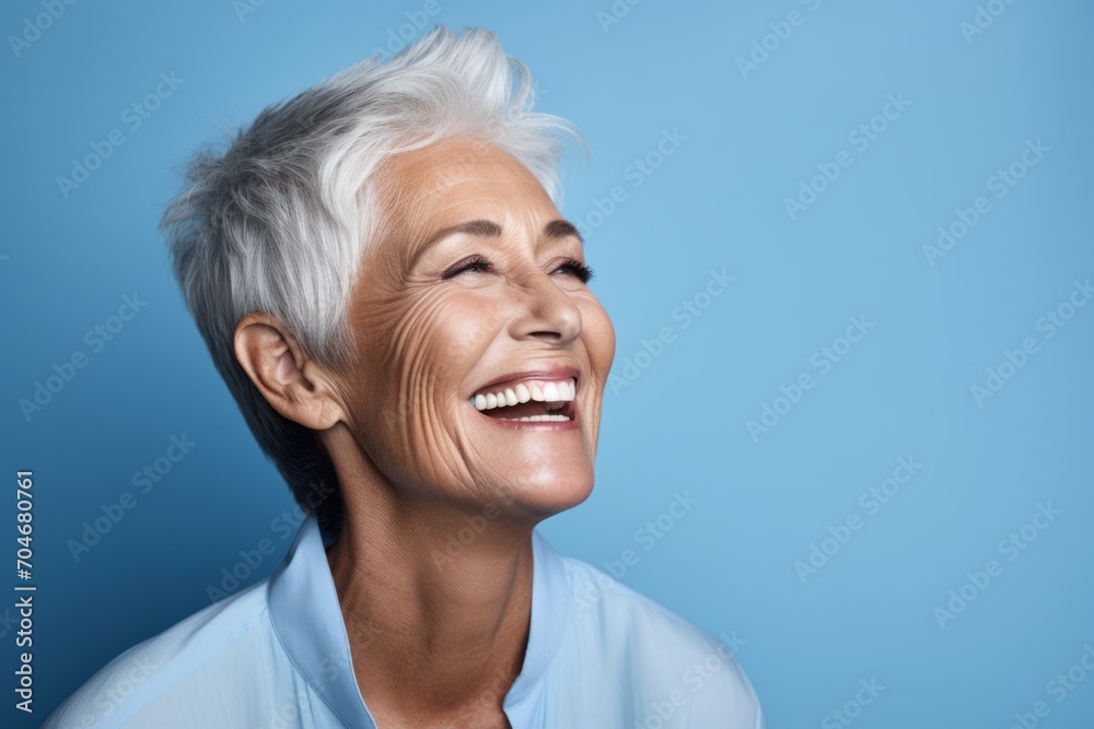 Portrait of a happy senior woman smiling at camera against blue background Portrait of a happy senior woman smiling at camera against blue background