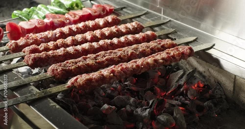 Adana kebab barbecue on charcoal grill. Meat and vegetables on grill. Traditional Turkish kebab grilled on skewers photo