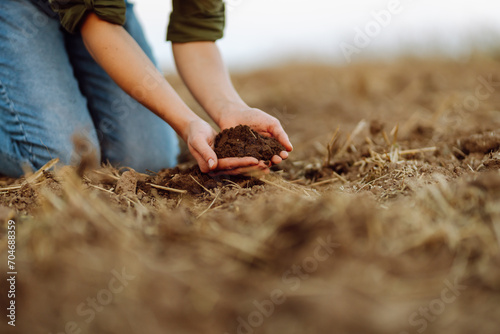 Close-up of a woman farmer's hands with black soil in an agricultural field. A woman agronomist holds the soil, checks its quality before sowing. Ecology, gardening concept.