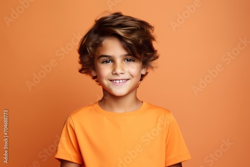 Portrait of a cute little boy with curly hair on a orange background