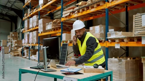 Warehouseman checking delivery, stock in warehouse on computer, pc. Warehouse manager using warehouse management software, app. photo