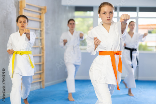 Kata karate woman teacher conducts female classes and performs movements and fighting techniques together with young girls students to prepare them for competitions.