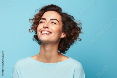 Portrait of beautiful happy smiling young woman with curly hair  over blue background