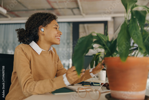 Smiling female manager is listen music in headphones during break time in office. High quality photo