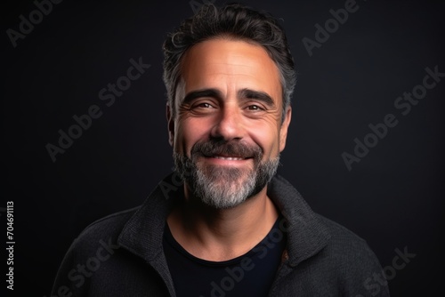 Portrait of a handsome bearded Indian man smiling on a black background