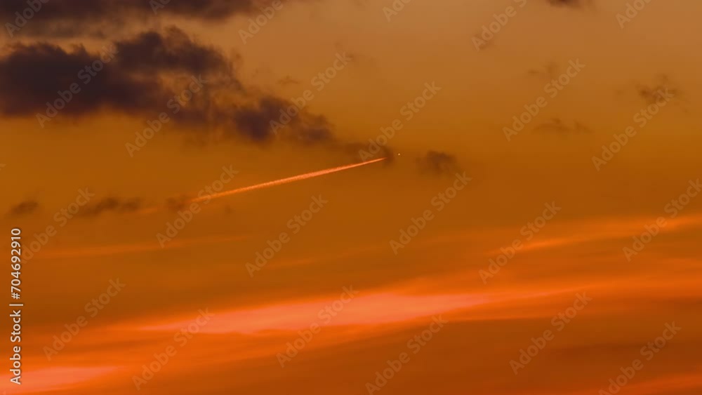 Orange luminosity jet from high altitude airplane at sunset sky Orange luminosity jet from high altitude airplane at sunset sky