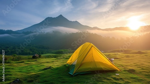 Small Yellow and Green Camping Tent Picnic on green lawn behind mountain sunrise morning sky background, Recreation and outdoor travel concept. 