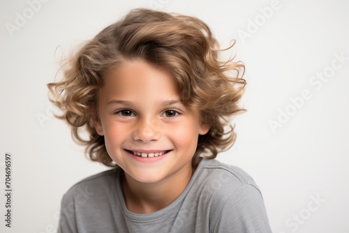 Portrait of a smiling little boy with curly hair on a white background