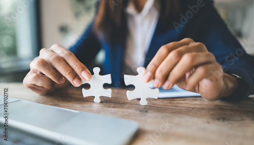 Businesswoman's hand assembles jigsaw puzzle on desk, symbolizing strategy, success, and problem-solving in business