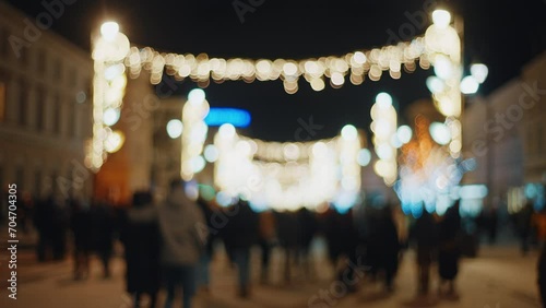 Defocused blurred Christmas background view of winter city street decorated with festive New Year's illumination decorations and unrecognizable people crowd walking to xmas market photo