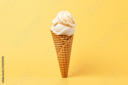 A classic vanilla ice cream cone isolated on a solid yellow background, waffle cone