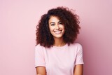 Happy young african american woman with curly hair on pink background