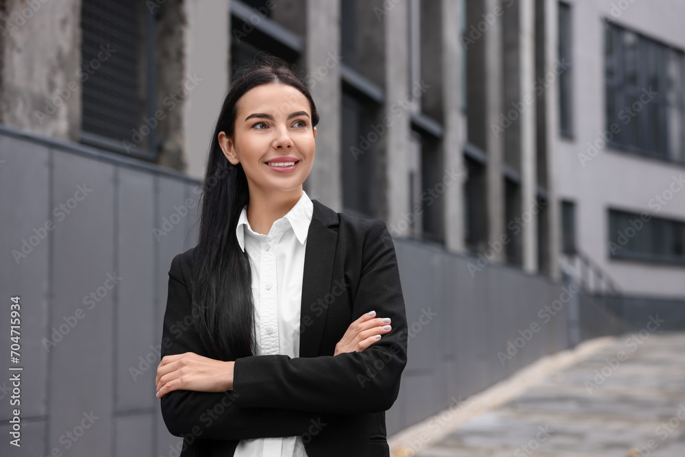 Portrait of smiling woman with crossed arms outdoors, space for text. Lawyer, businesswoman, accountant or manager Portrait of smiling woman with crossed arms outdoors, space for text. Lawyer, businesswoman, accountant or manager