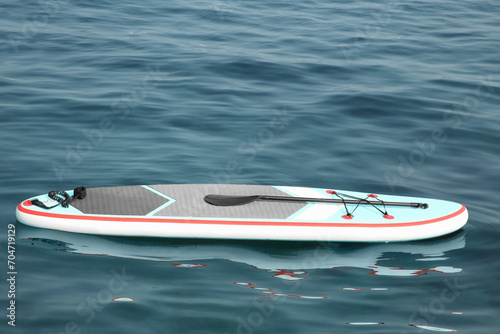 One SUP board with paddle on water in sea, space for text