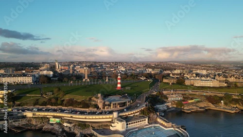 Cinematic aerial view of Plymouth, England at the sunset. Drone view of Smeaton's tower, Hoe Park, Plymouth Harbour during holden hour. 