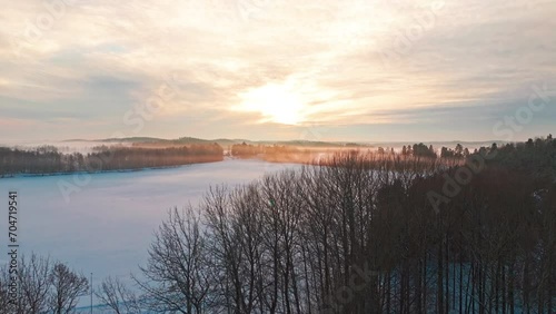 Wallpaper Mural Flying over cape to reveal vast nordic scandinavian landscape with forest covered in snow and ice, fog engulfing the beatiful scenery. Sun paints sky orange and lake and fields are seen between woods. Torontodigital.ca