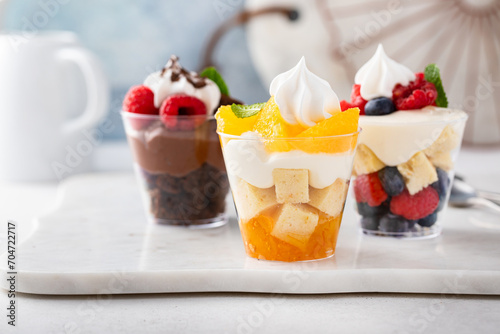 Three desserts in cups, variety of trifles with orange, chocolate and berry