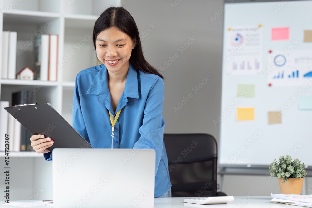 Businesswoman standing at desk and using laptop to analysis data and plan statistics and business strategies Businesswoman standing at desk and using laptop to analysis data and plan statistics and business strategies