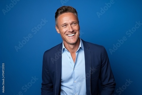 Portrait of a handsome mature man laughing while standing on blue background