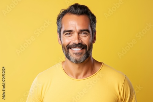 Handsome middle-aged man smiling at camera over yellow background