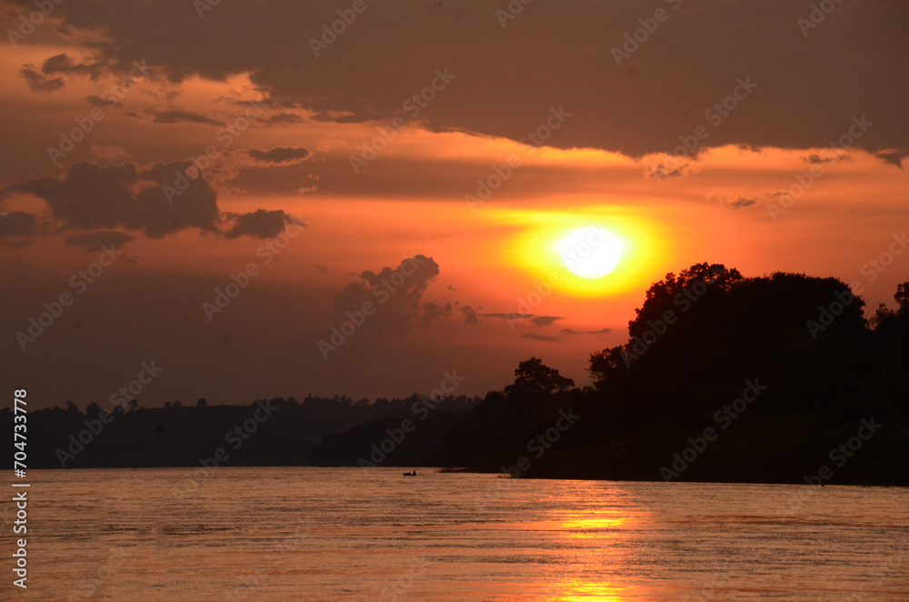 Naklejka premium Silhouette tranquil season wilderness serene landscape. Tranquil lake countryside sunrise seaside reflection. Tropical amazing dramatic golden sky on sunset over scenic river lake seascape ocean.