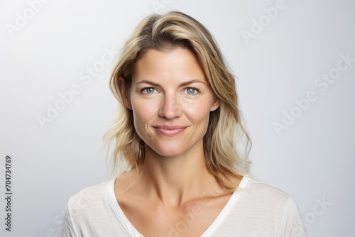 Portrait of a beautiful blond woman smiling at the camera on a gray background