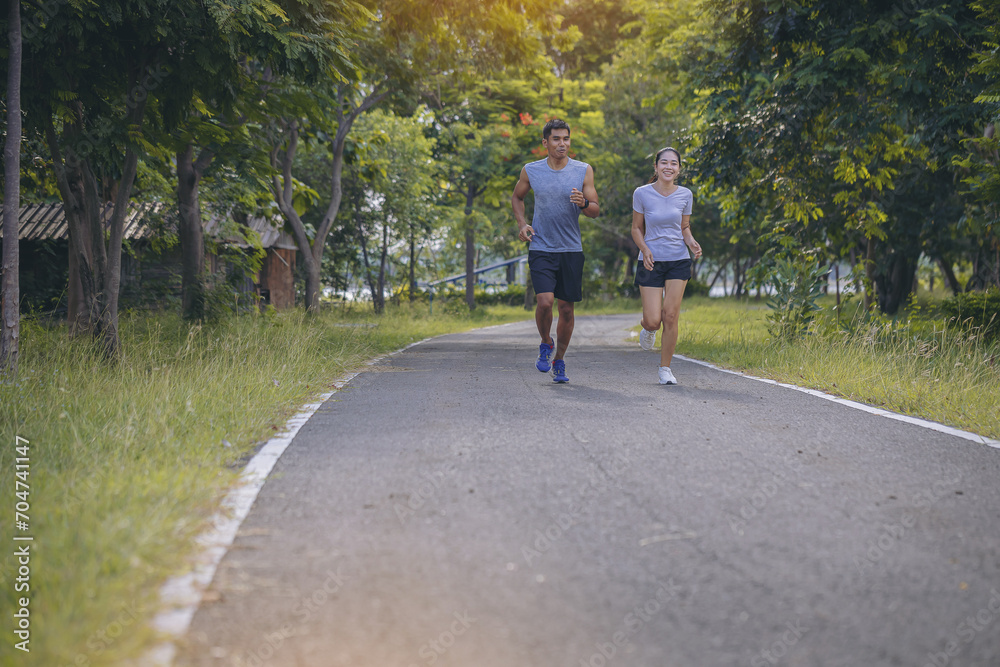 Young couple running together on road. Couple, fit runners fitness runners during outdoor workout with sunset background.