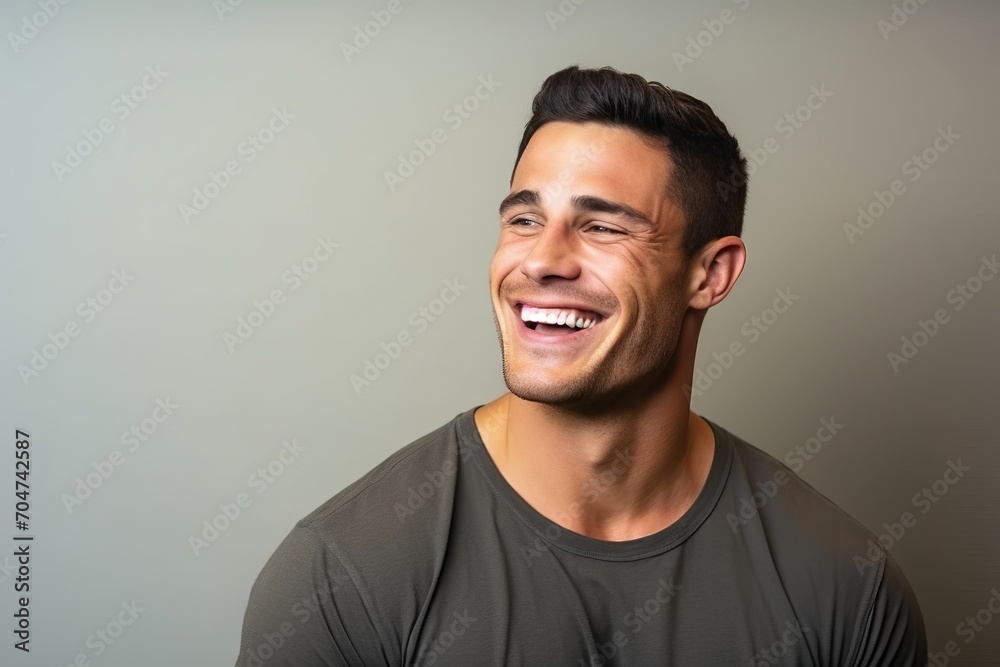 Portrait of a handsome young man laughing against a grey background. Portrait of a handsome young man laughing against a grey background.