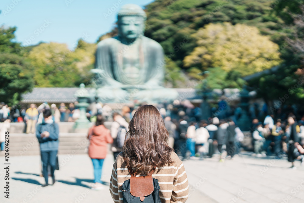 Obraz premium Woman tourist Visiting in Kamakura, Kanagawa, Japan. happy Traveler sightseeing the Great Buddha statue. Landmark and popular for tourists attraction near Tokyo. Travel and Vacation concept