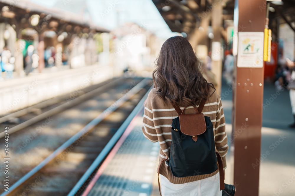 Woman tourist waiting train and Visiting in Kamakura, Kanagawa, Japan. happy Traveler sightseeing Kamakura train station. Landmark and popular for tourists attraction near Tokyo. Travel and Vacation