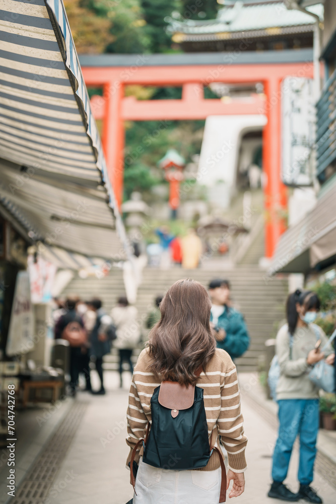 Woman tourist Visiting in Enoshima Island, Fujisawa, Kanagawa, Japan. happy Traveler sightseeing Enoshima Shrine. Landmark and popular for tourists attraction near Tokyo. Travel and Vacation concept