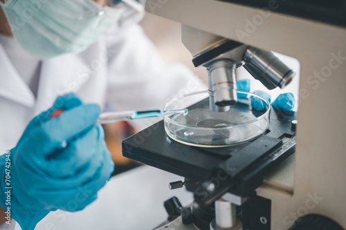 Female researchers are experimenting with pipette dropping a sample into a test tube in an experiment research in laboratory...