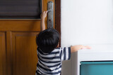 curious toddler kids trying to pull the door handle to open the wooden door