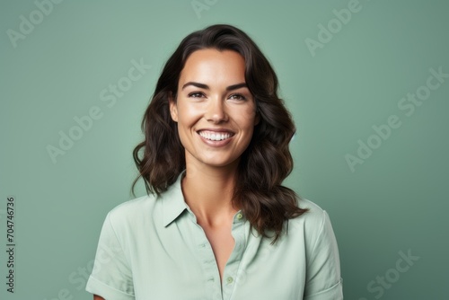 Portrait of happy smiling young woman in green shirt, over green background