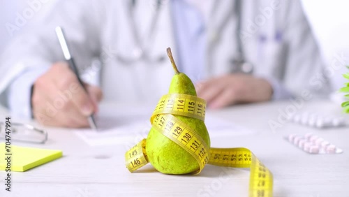 Fruit as Healthy eating concept, Doctor taking notes, pear and measure tape photo