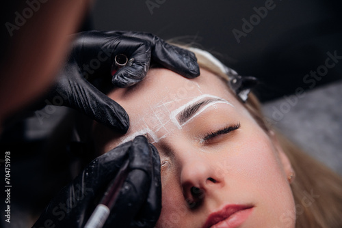 The makeup artist performs permanent makeup. Professional makeup and facial care. Eyebrow and lip tattooing. Cosmetologist. Beauty salon.