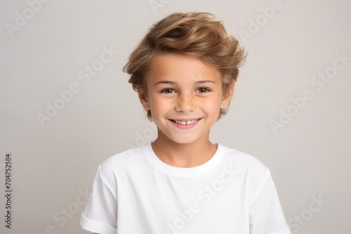 Portrait of a cute little boy with blond hair on grey background