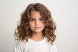 Portrait of a cute little girl with long curly hair on a gray background
